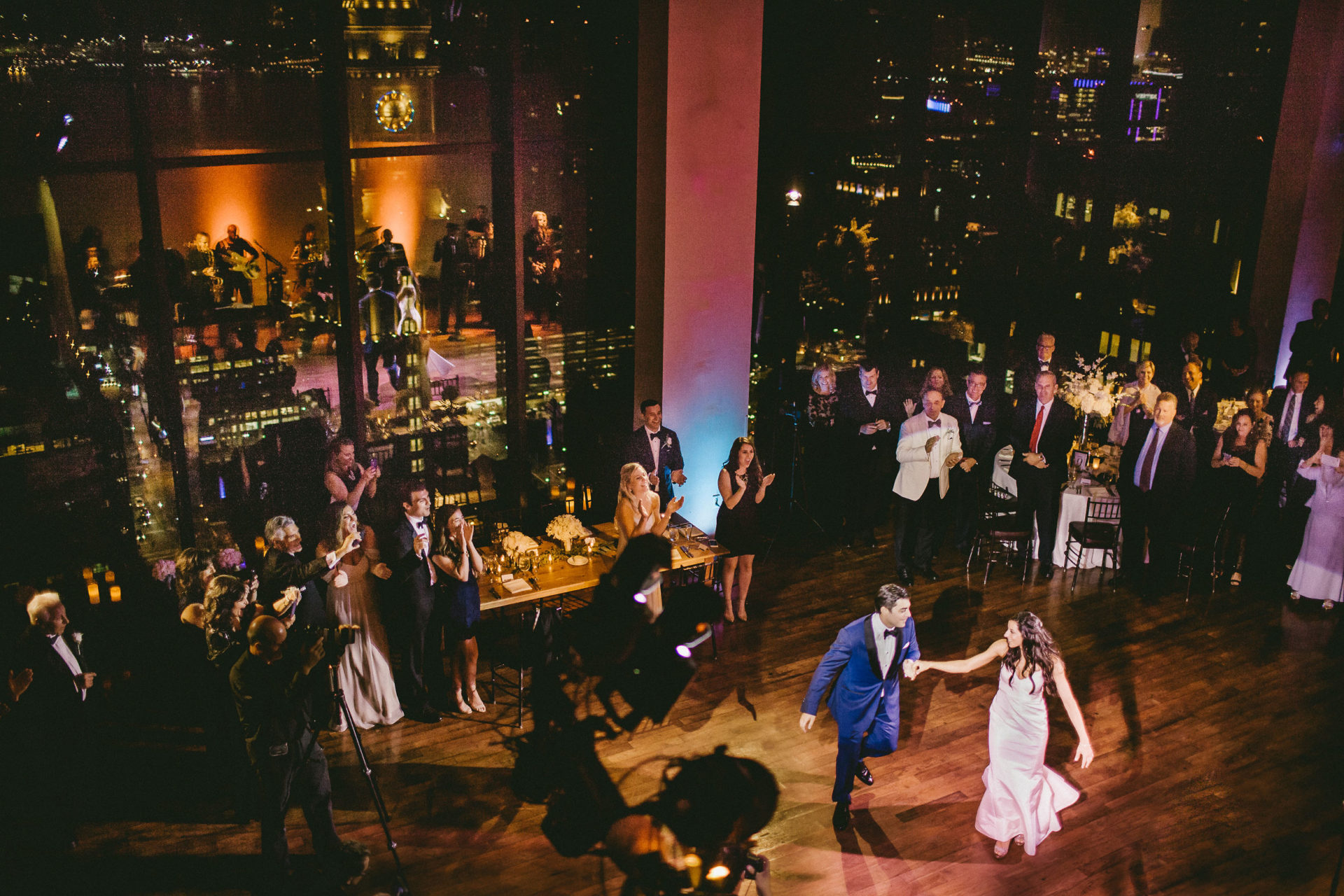 a bride and groom dance in a ballroom with a view of the San Francisco skyline near the Ferry Building