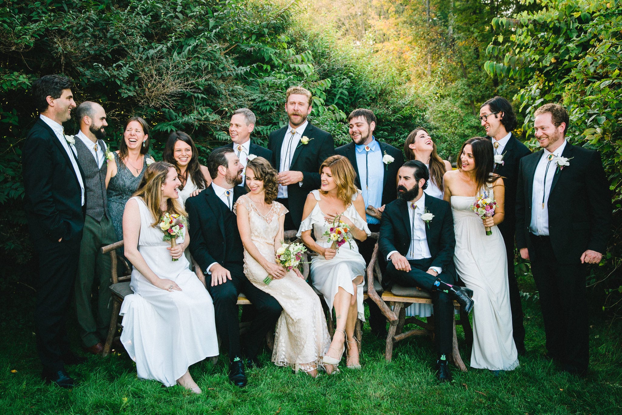 a wedding party looking at eachother and laughing while preparing for a posed portrait