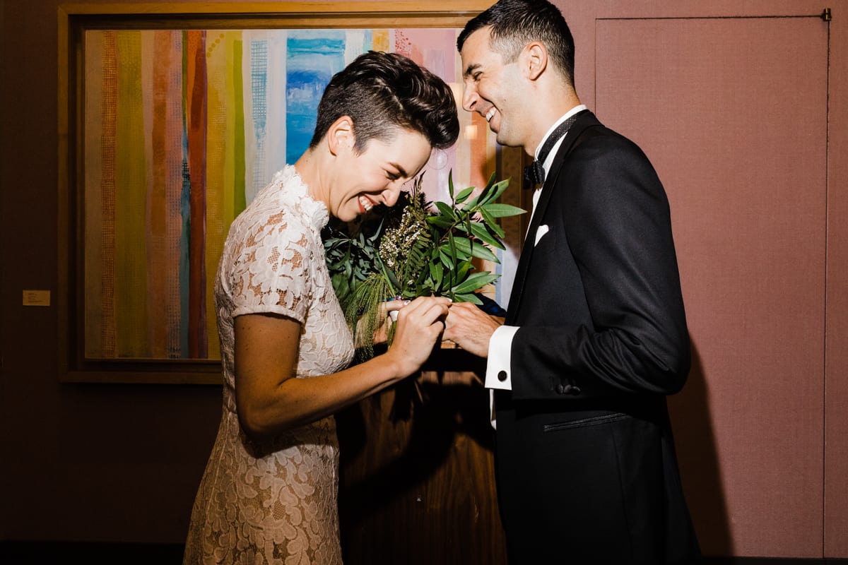Bride and groom are grinning as bride puts ring on grooms finger