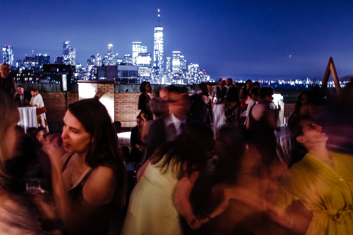 Blurry dancing crowd on a rooftop with downtown Manhattan in the background