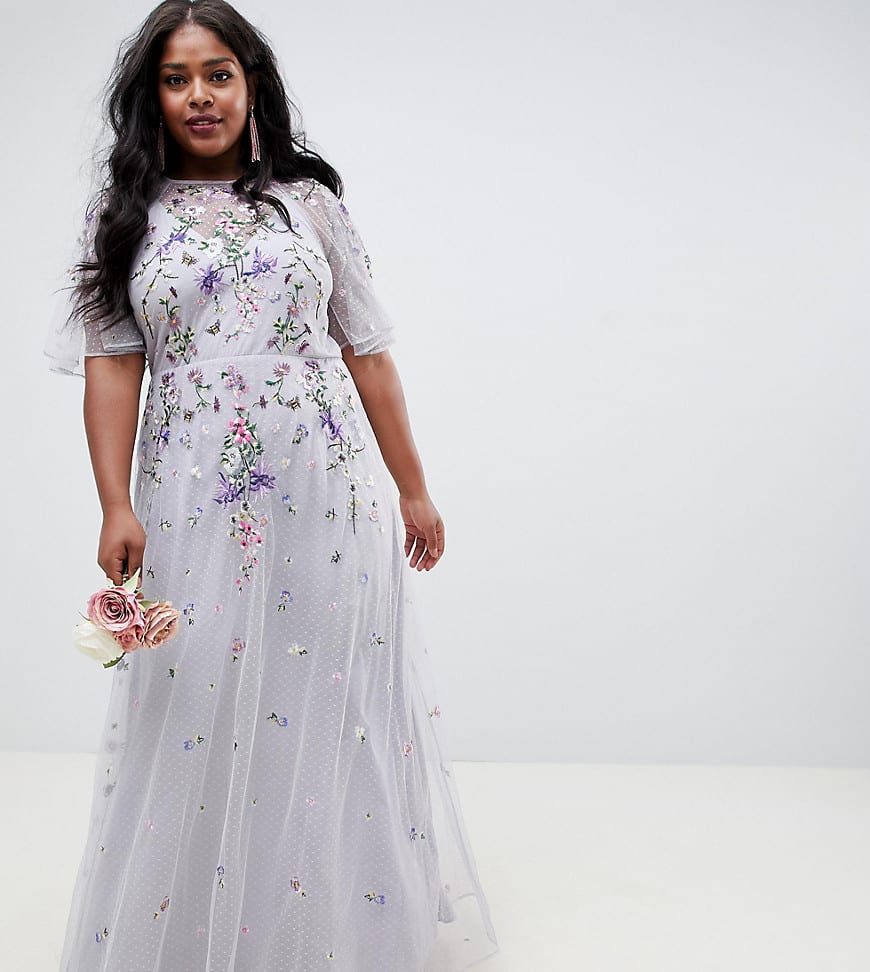 plus size black woman with long hair wearing a light grey formal dress with embroidered flowers