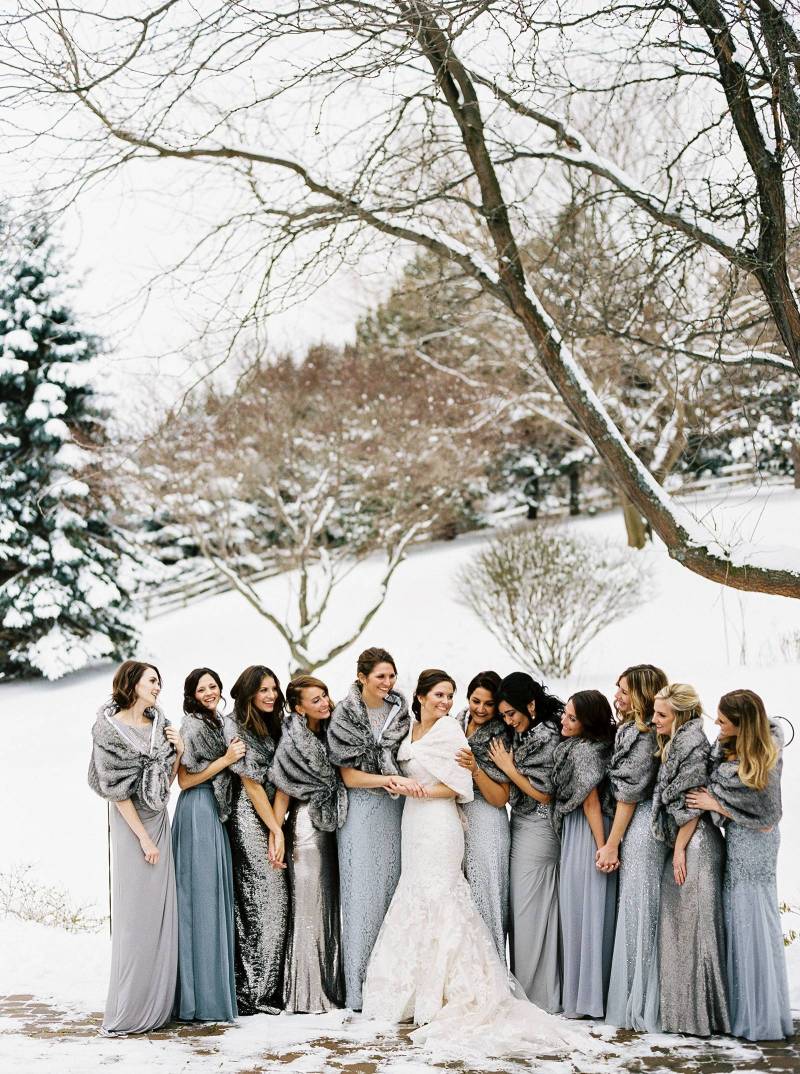 Winter wedding ideas for a modern, winter minimalist wedding party—Group of gown-clad women standing in snowy landscape