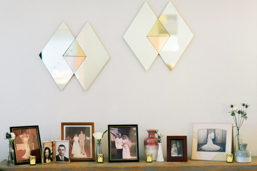 A table with a variety of frames with vintage images of married couples sits below two geometric diamond mirrors