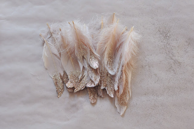 Pile of feathers in winter wedding colors: white and cream feathers dipped in gold glitter
