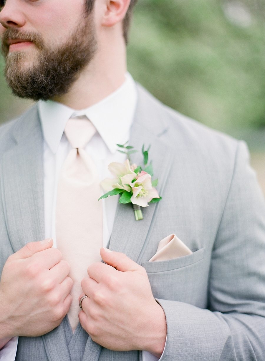 Closeup of man wearing winter wedding colors: a cream tie with grey suit