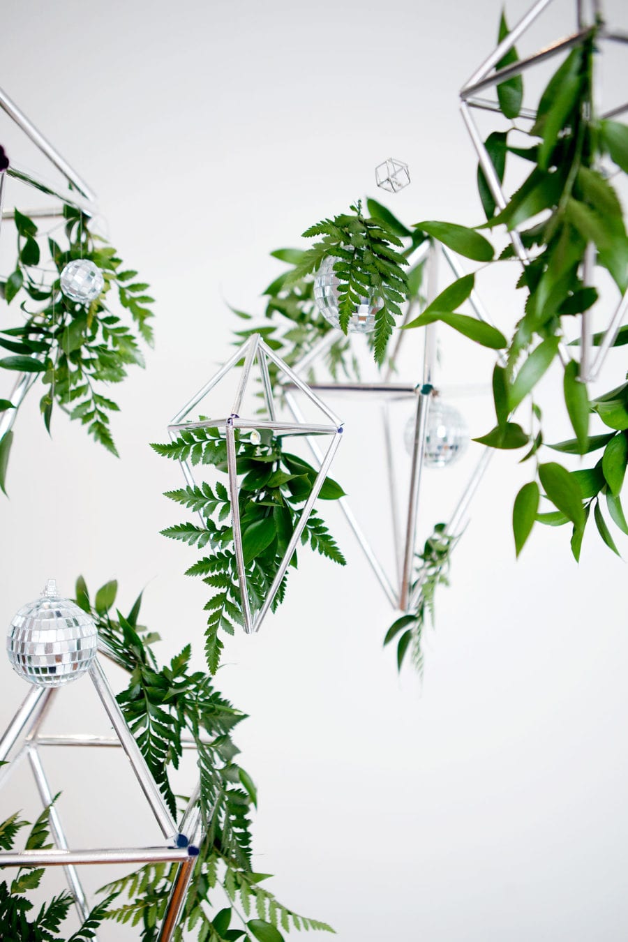 Winter wedding ideas for decor—Silver Geometric decor hanging amidst ferns