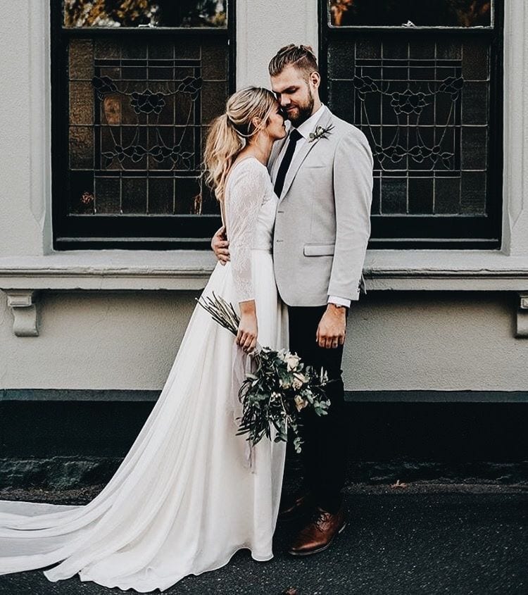 Winter wedding ideas for long-sleeved gown—Woman in white gown with man, holding a bouquet