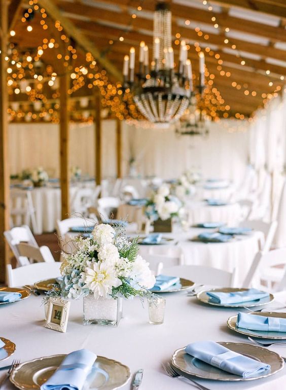 Decorated and lighted room with tables in winter wedding colors: silver and blue place settings