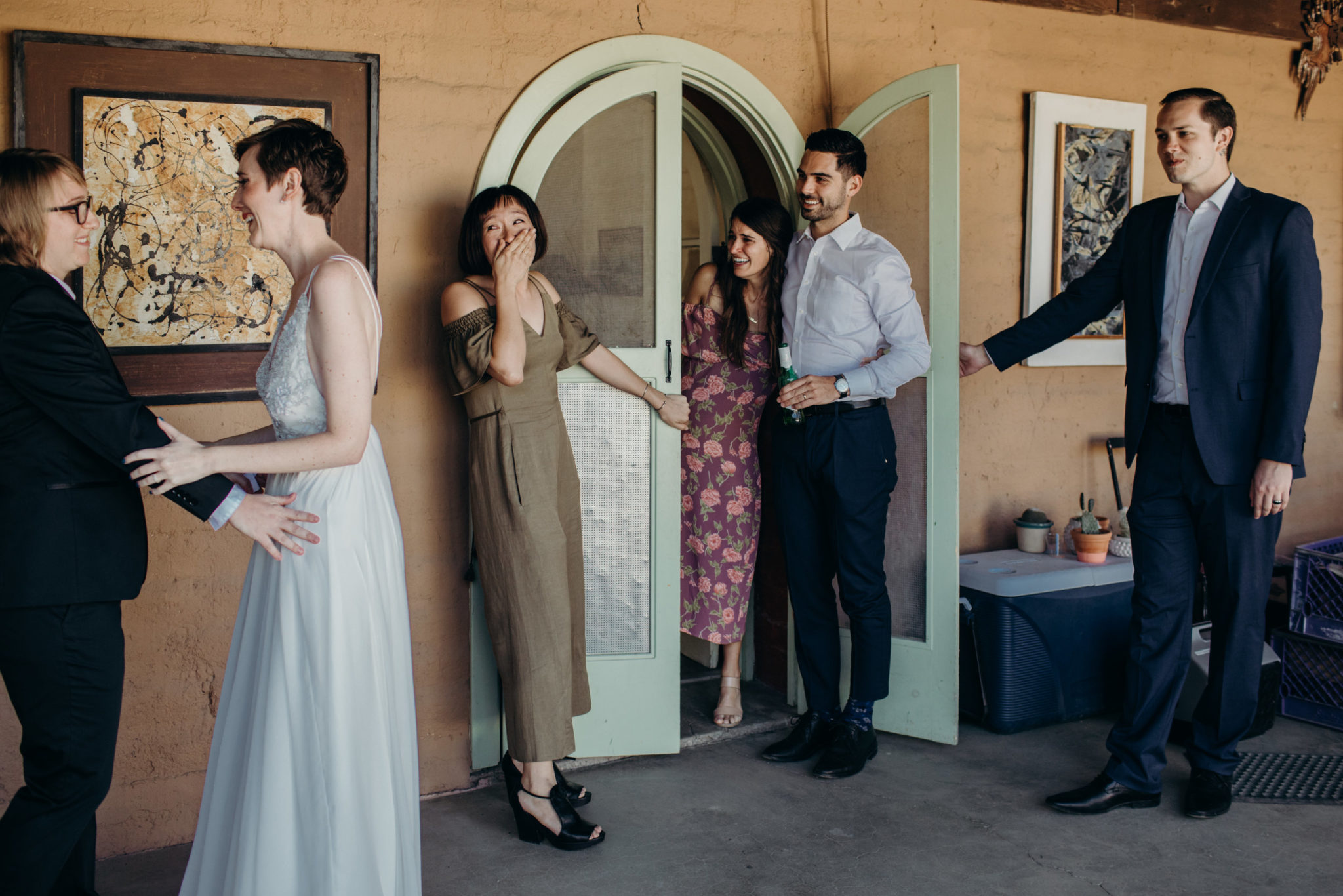 The reaction of several guests to a queer wedding couple experiencing their first look is documented in a photo by Betty Clicker