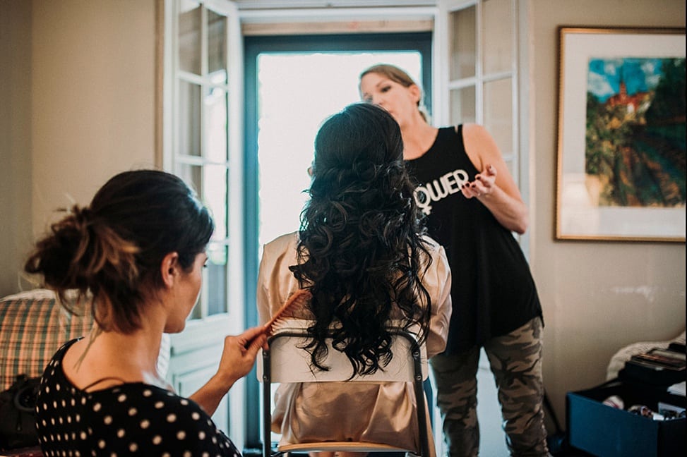 a woman with long black hair gets her styled and makeup done for her wedding