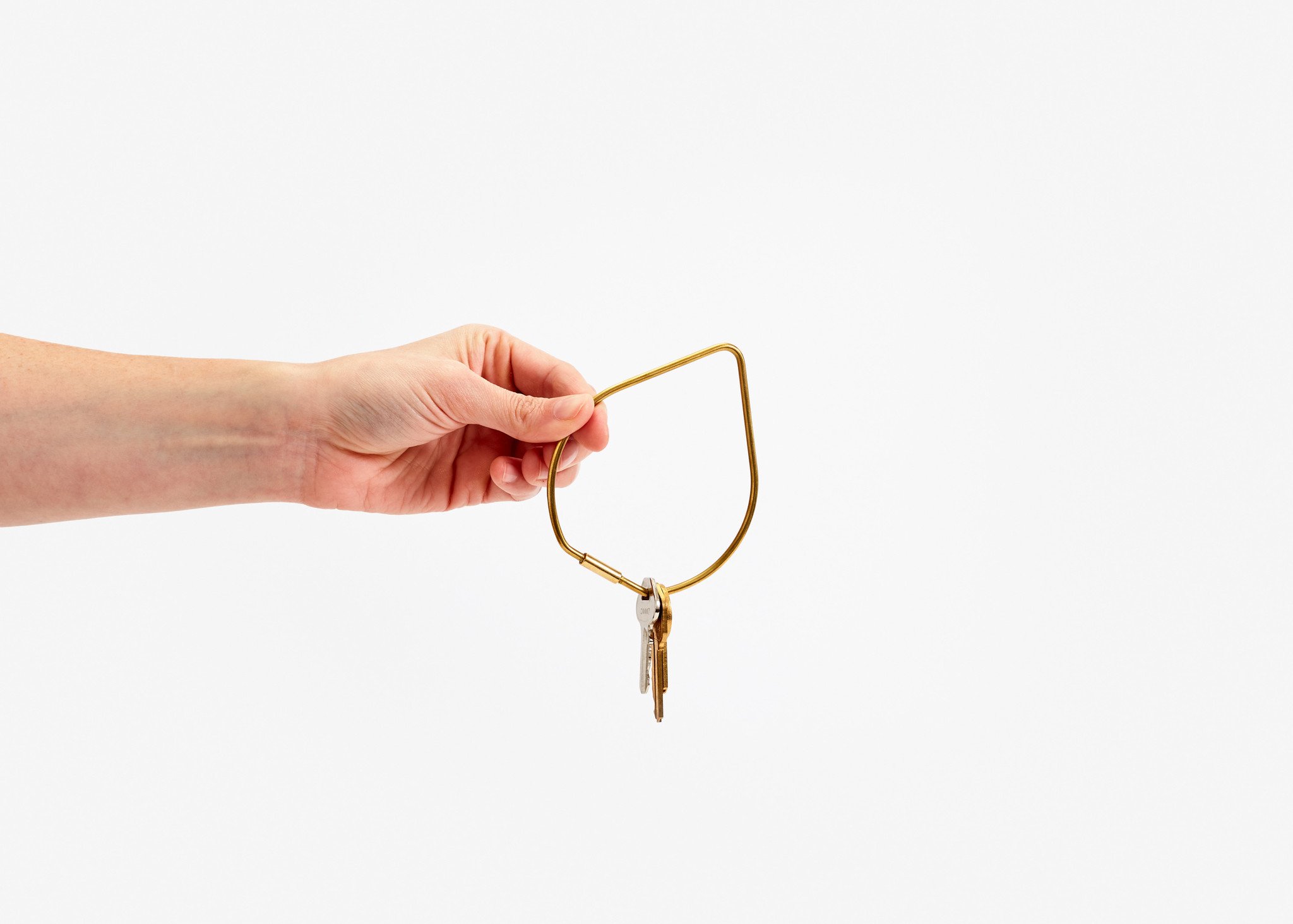 a hand holding a tear drop shaped key ring in front of a white background