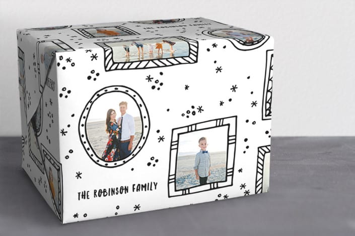 a present packaged in personalized black and white wrapping paper with family photos on it
