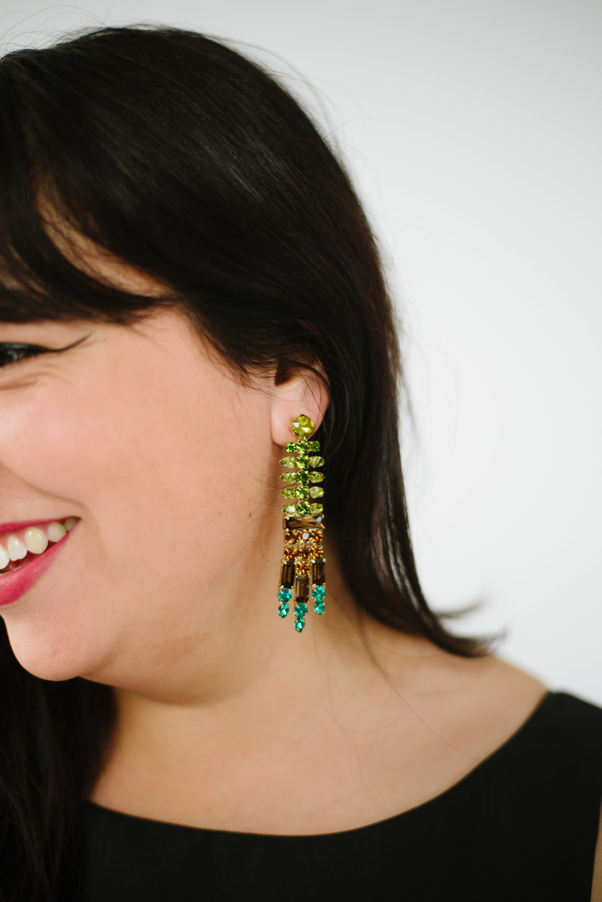 A close up photo of a woman wearing a lime green, brown and turquoise statement earring from Walmart