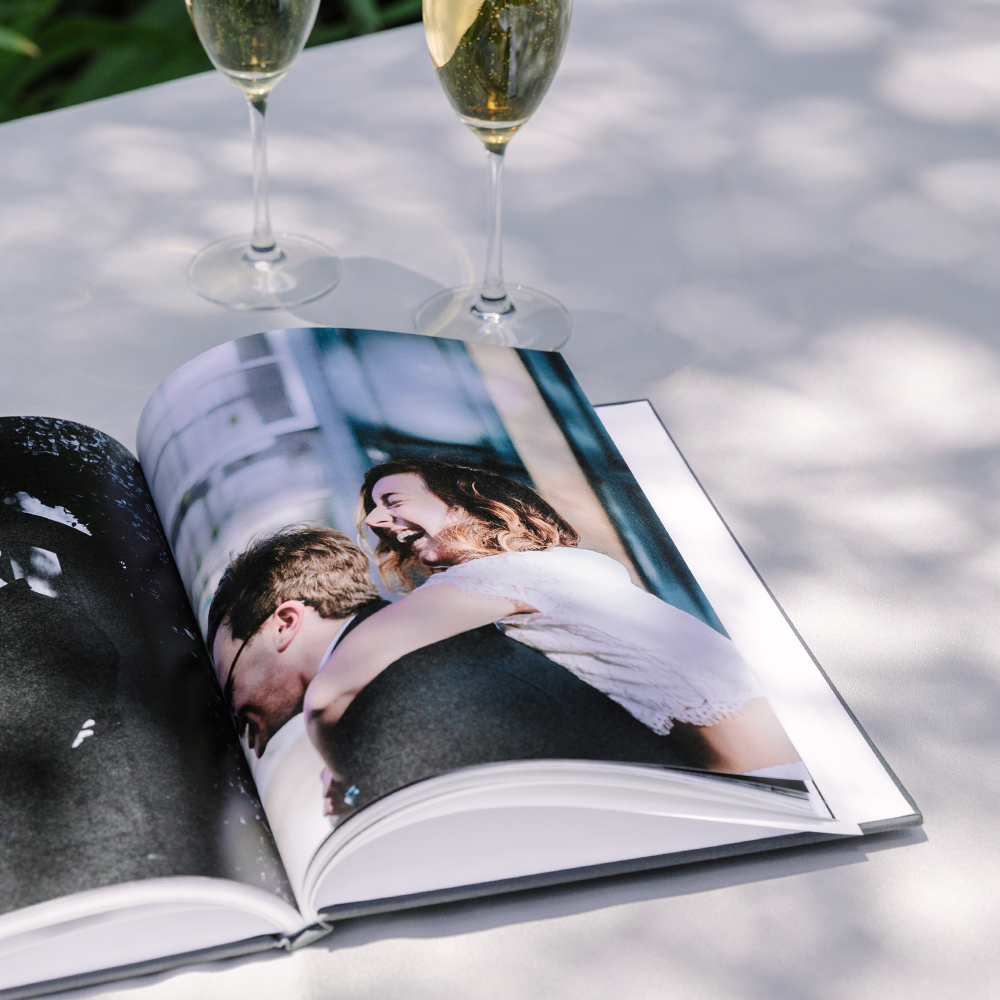 An open wedding album from Artifact Uprising near two glasses of champagne