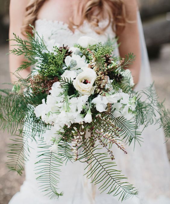 woman in white dress holding bouquet with fir sprigs