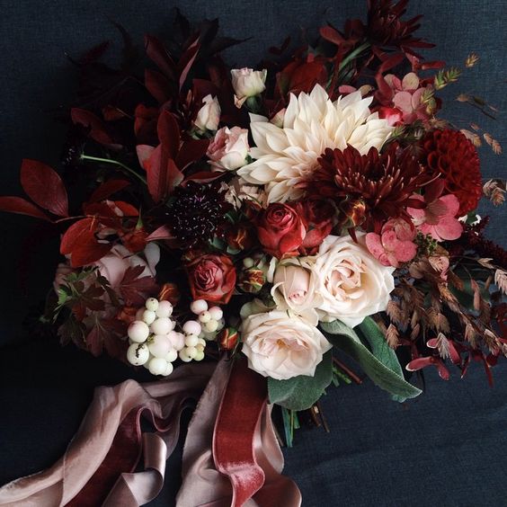 Bouquet in winter wedding colors: red, burgundy, white, and cream on a navy background, with velvet ribbons