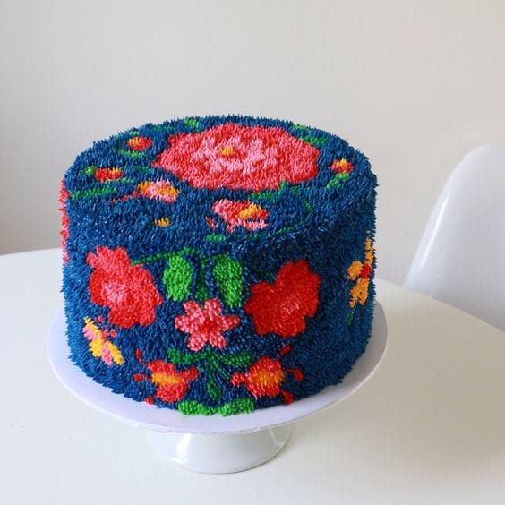 wedding ideas for cakes—colorful textured cake with red, pink, and yellow flowers on a dark blue background