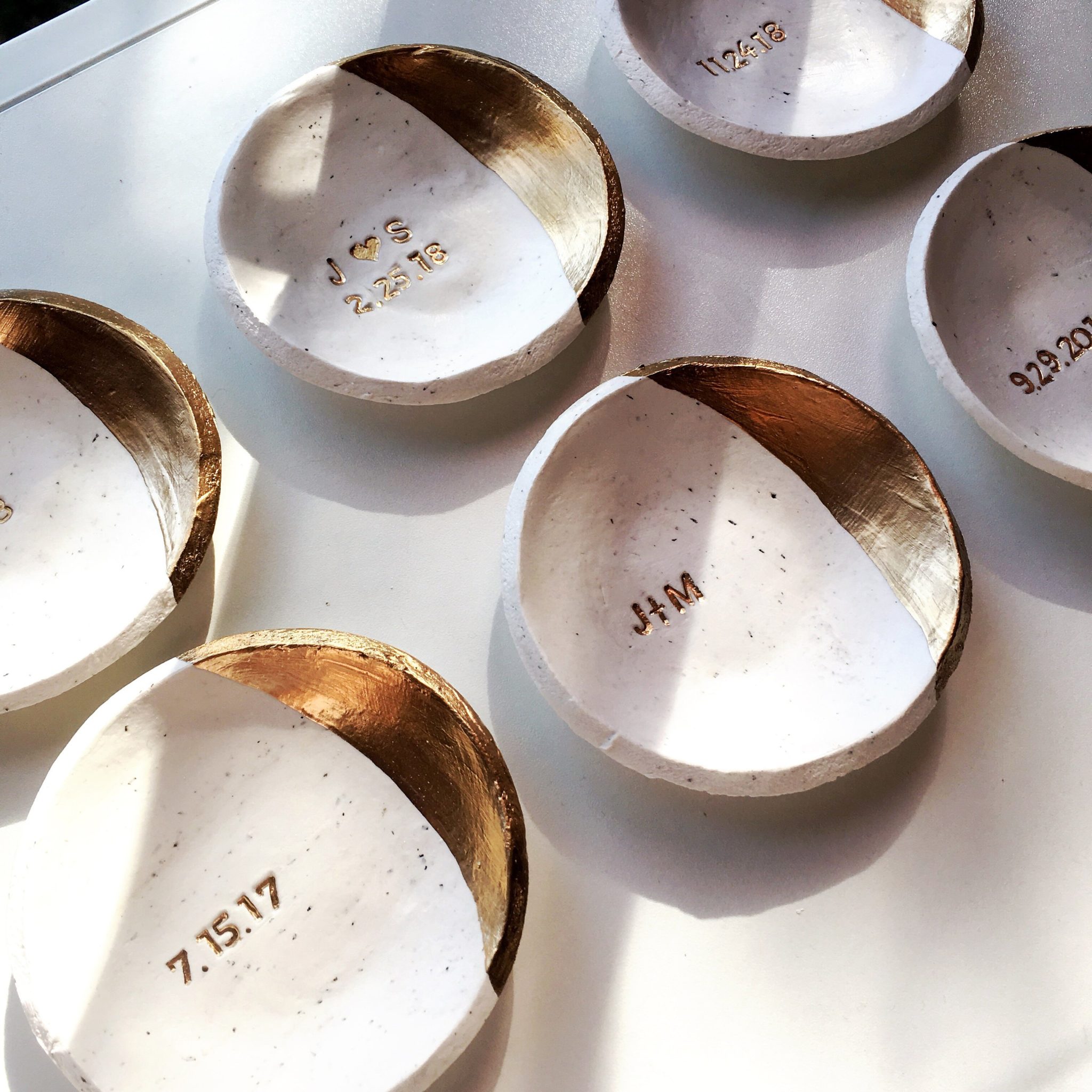 six white speckled clay ring dishes with gold accents and personalized initials in the center