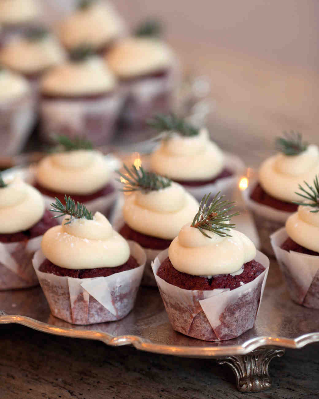 Winter wedding ideas for sweet treats—A tray of cupcakes topped with greenery on a table