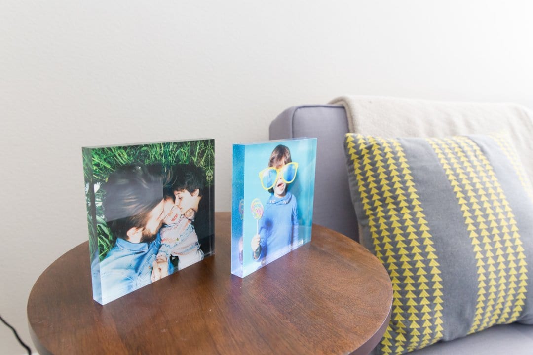 two acrylic photo frames sitting on a wooden side table