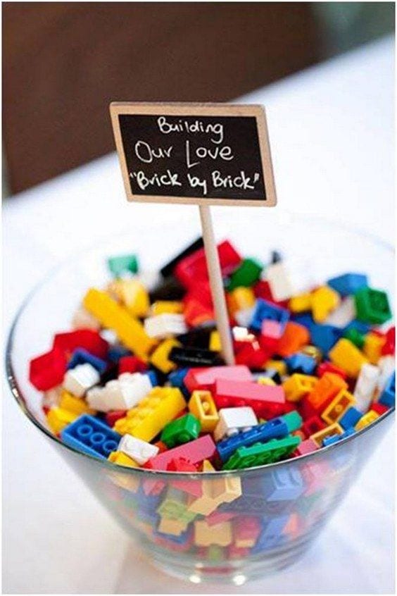 wedding ideas for activities—legos in a glass bowl on a table with a sign that reads "Building our love brick by brick" 