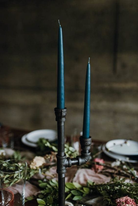 wedding ideas for centerpieces—dark teal colored candles stick in a black industrial pipe candelabra
