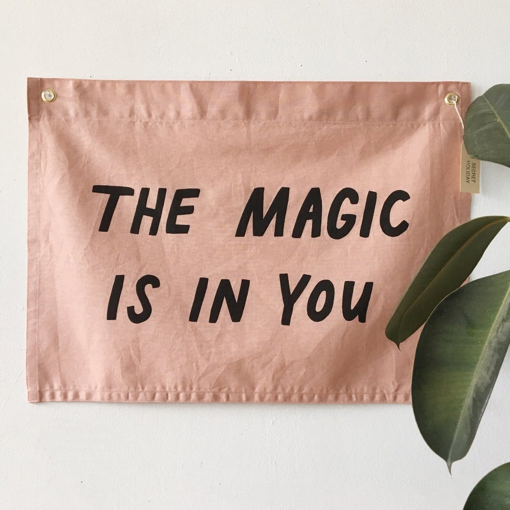 a mauve flag that says "THE MAGIC IS IN YOU" in black writing
