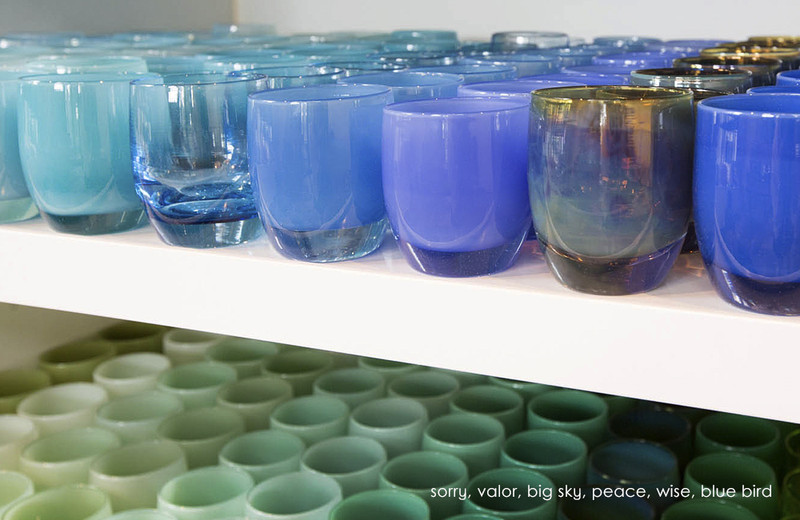 a shelf full of blue and green hand-blown votive candle holders