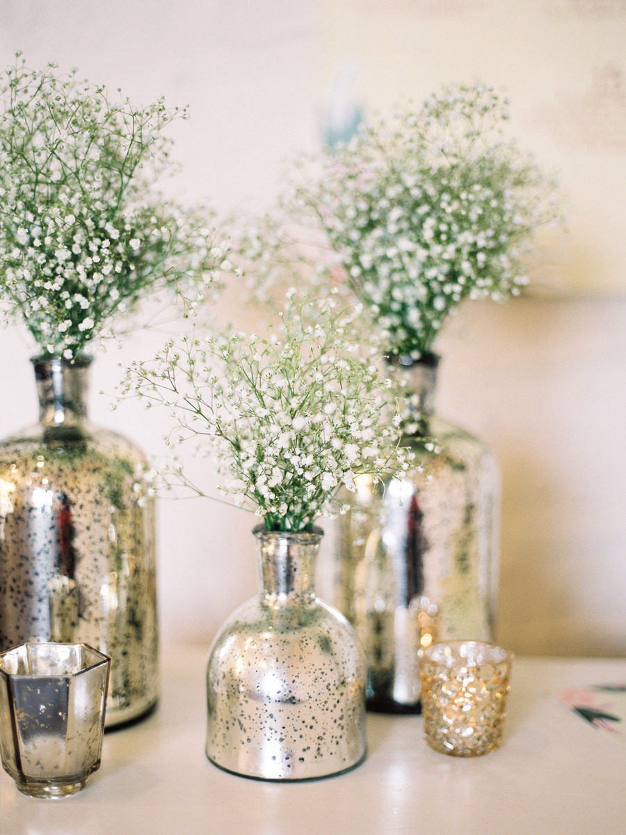 flower arrangements in winter wedding colors: silver mercury glass bottles holding baby's breath on table