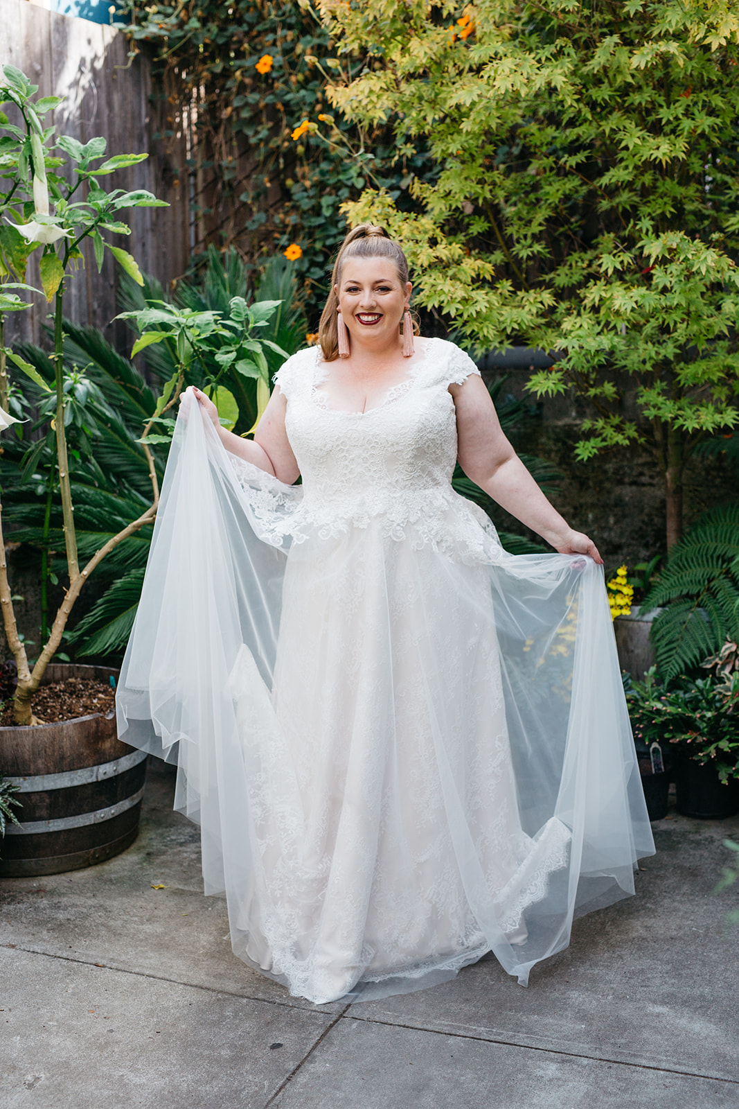 model wearing a romatic vintage inspired scoop neck lace wedding dress with sleeves and a tulle overlay from the a practical wedding plus size wedding dress collection