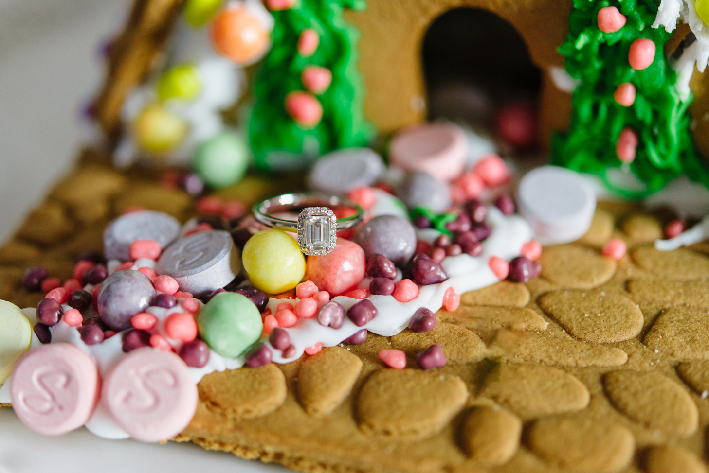 Walmart synthetic diamond engagement ring sits on a colorful candy path of a gingerbread house