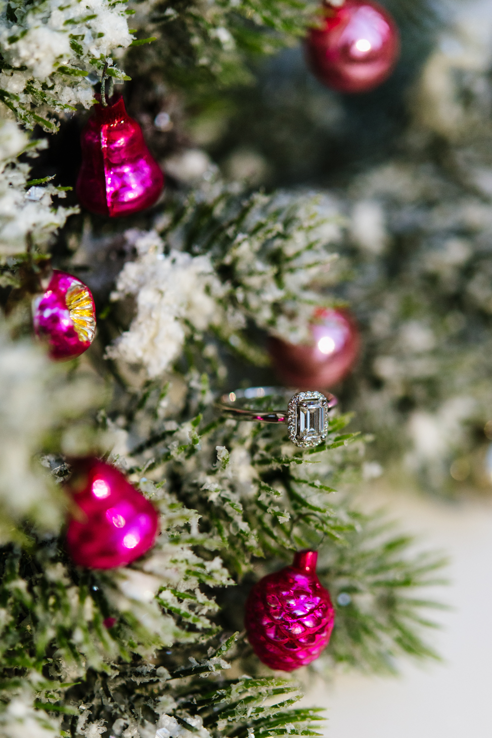 Walmart synthetic diamond engagement ring sits on a snow frosted christmas tree branch surrounded by hot pink glass ornaments