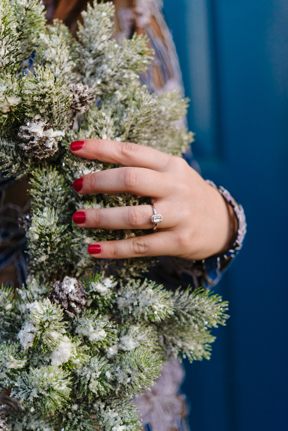 Woman's hand holds frosted wreath showing her Walmart synthetic diamond solitaire engagement ring