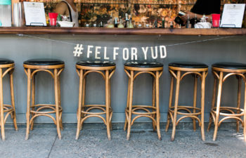 Barstools in front of a bar with a sign hanging above that reads "#FELFORYUD"