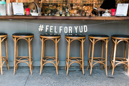 Barstools in front of a bar with a sign hanging above that reads "#FELFORYUD"