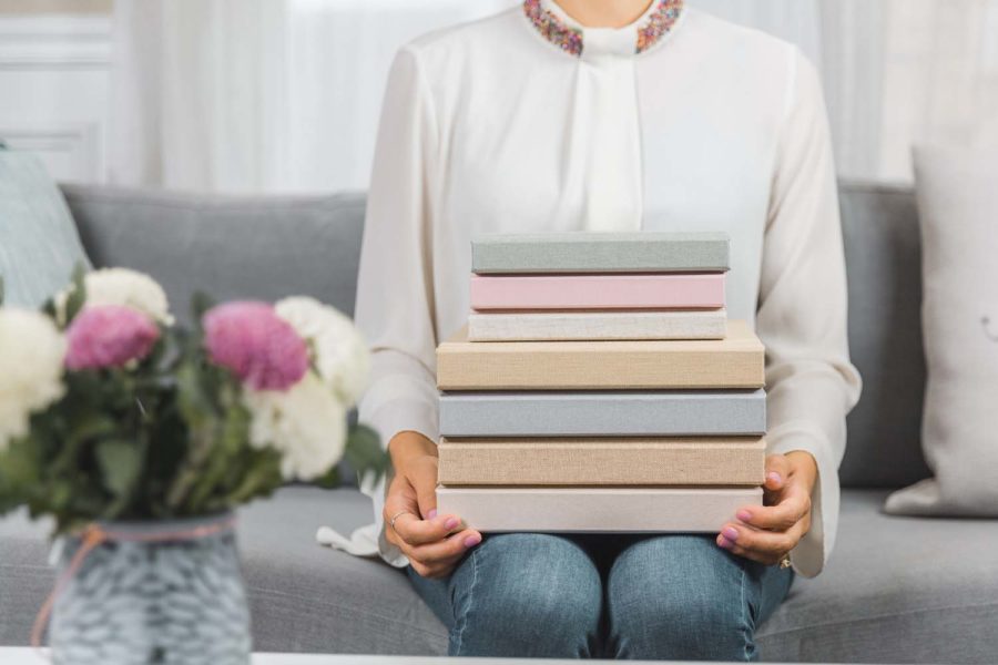 shot of woman holding a stack of flat lay wedding albums by Albums Remembered with linen covers in pastel tones