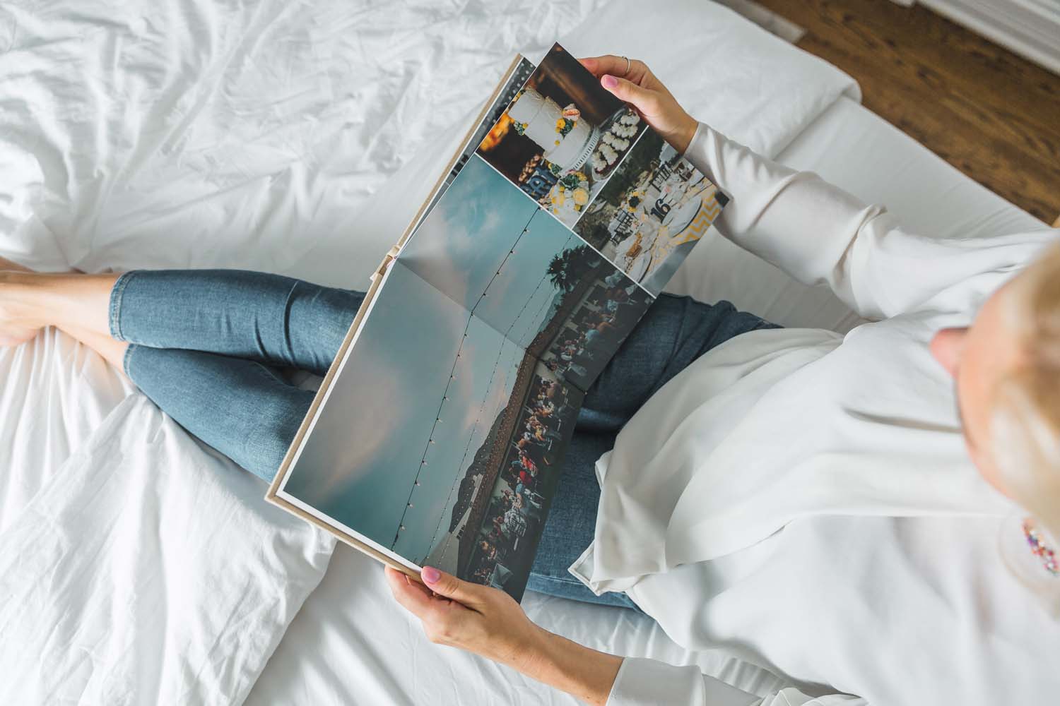overhead shot of a woman sitting on a bed looking at a flat lay wedding album by Albums Remembered