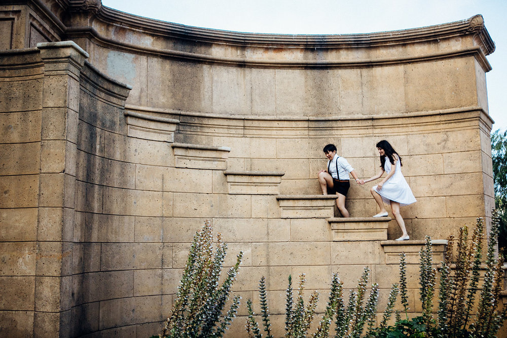 a queer couple climbs steps for an engagement photo