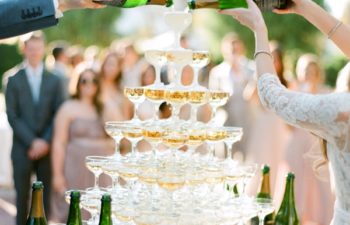 A bride and groom pour champagne onto champagne tower
