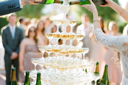 A bride and groom pour champagne onto champagne tower