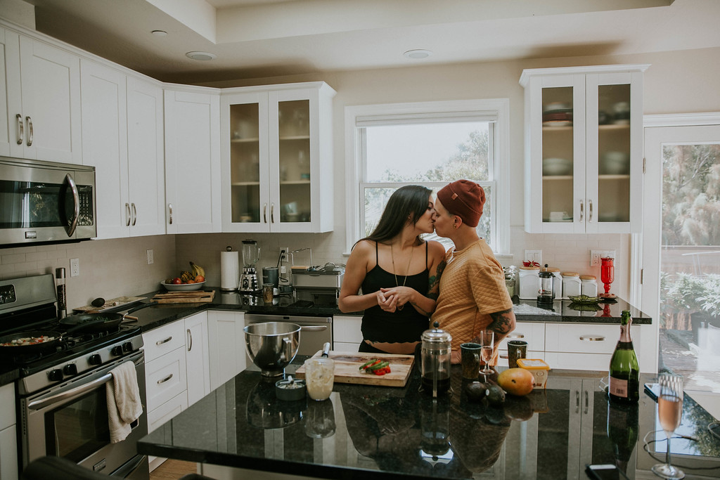 a queer couple kiss in their home kitchen for an LGBTQ engagement session