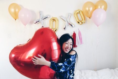 Woman holding balloon in front of balloon garland reading XOXO