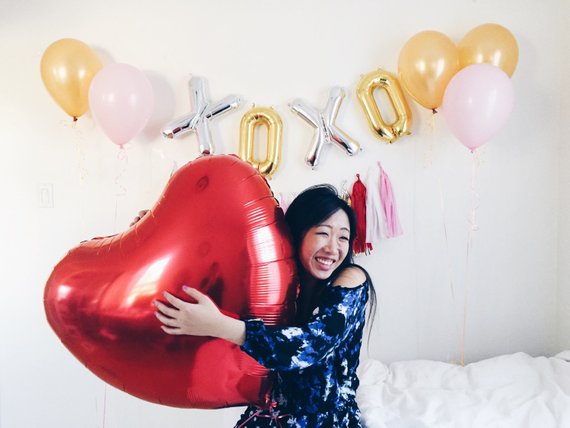 Woman holding balloon in front of balloon garland reading XOXO as an idea for bridal shower decorations