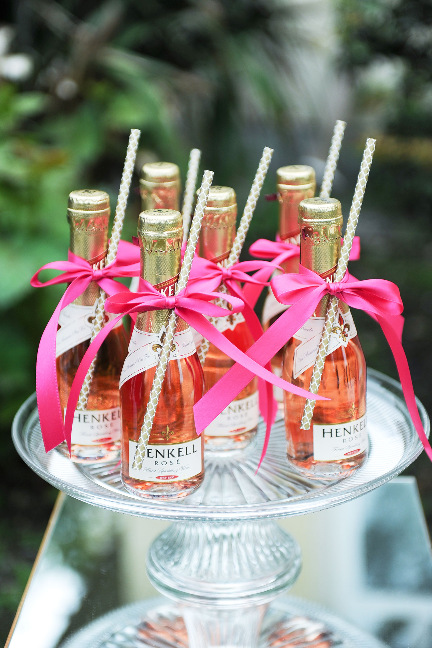 Platter of champagne bottles with straws and ribbons