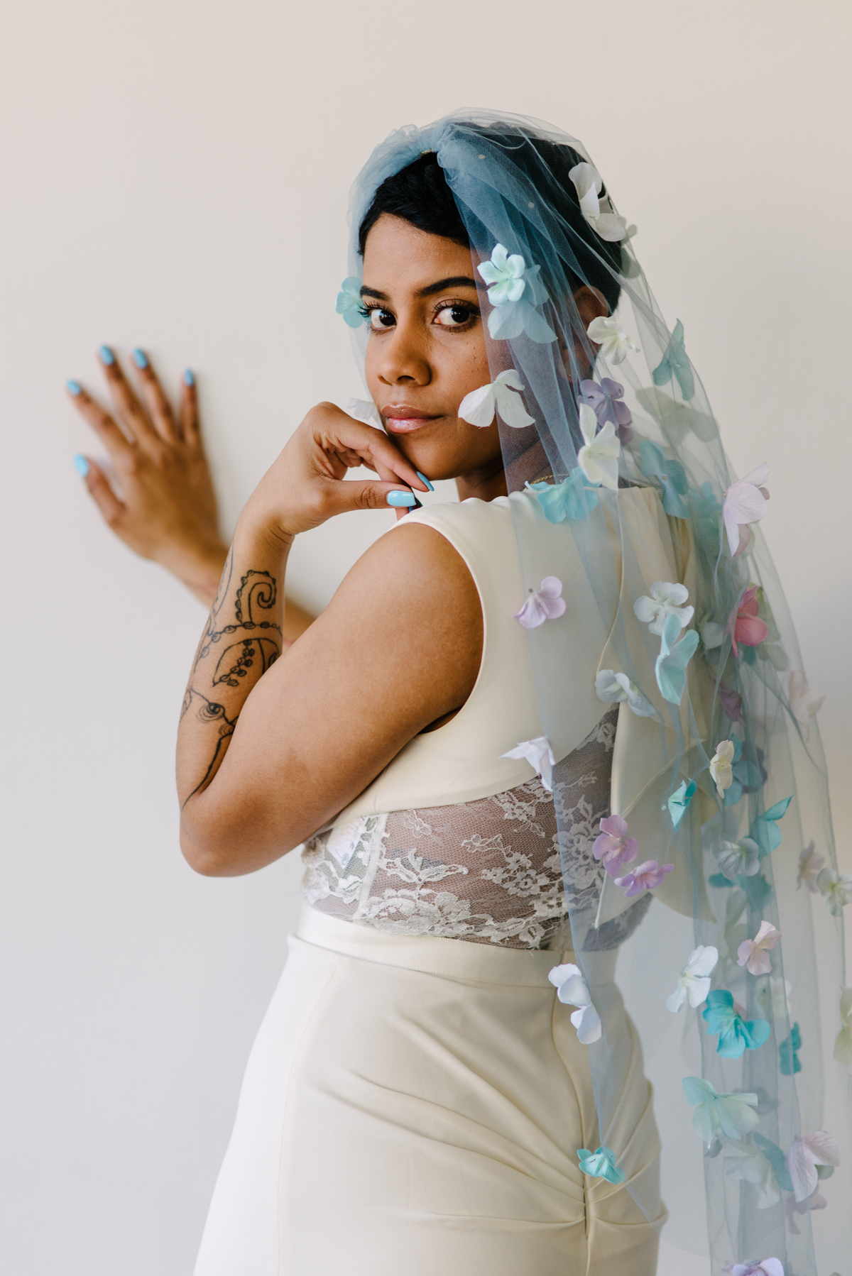 A woman looks over her shoulder back at the camera while wearing a light blue wedding veil