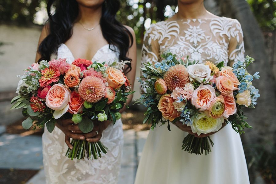 Two women wearing wedding dresses hold their bouquets