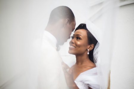 A bride in a veil smiles at the groom