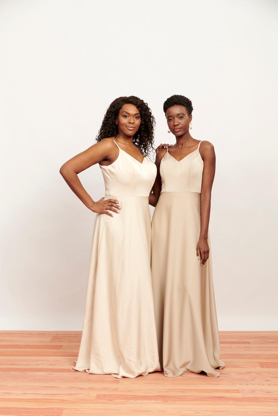 Two womxn stand in sleeveless bridesmaid dresses
