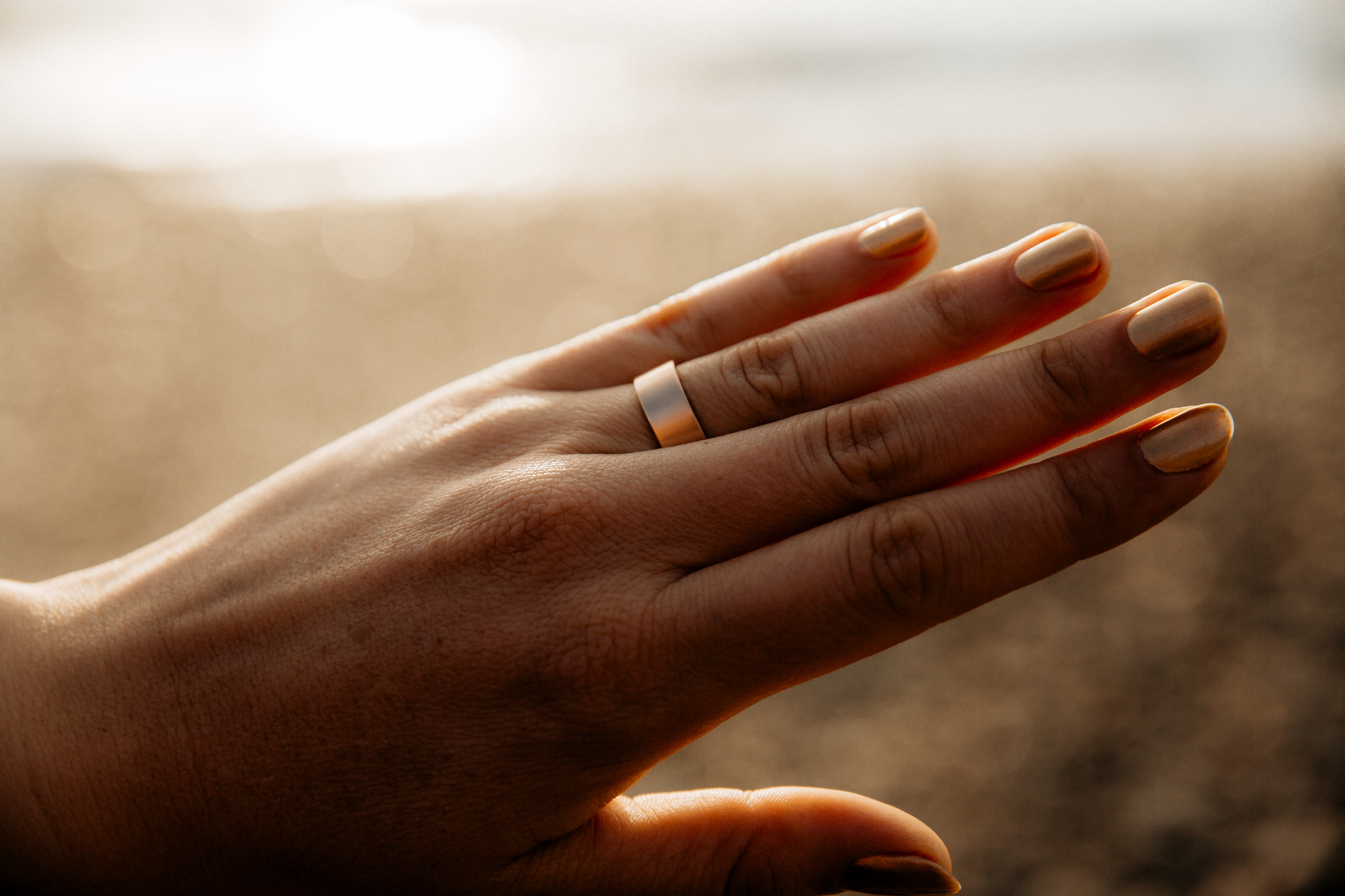 Close up of a Good Gold wedding band on a hand at sunset