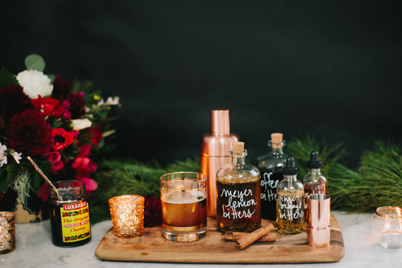 An assortment of cocktail accessories, bitters and ingredients on a wooden cutting board for bridal shower favors
